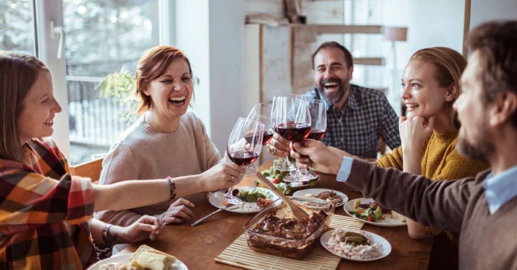 A family clinks wine glasses around a dinner table meal
