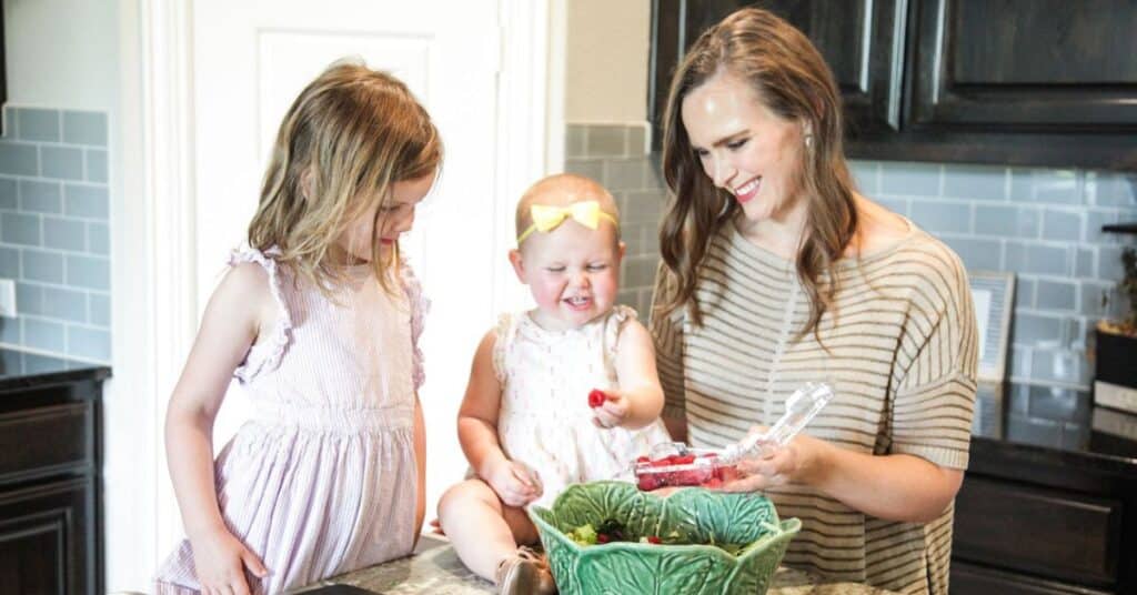 Katie Lovitt, dietitian for digestive issue symptoms, makes a fruit salad in her home kitchen with two of her young children