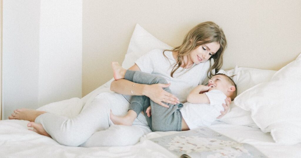 A mom cuddles her son in a bed, IBS symptoms in females