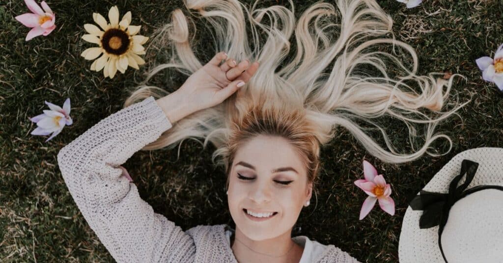 Smiling woman lays in grass surrounded by flowers, Setting Health Goals
