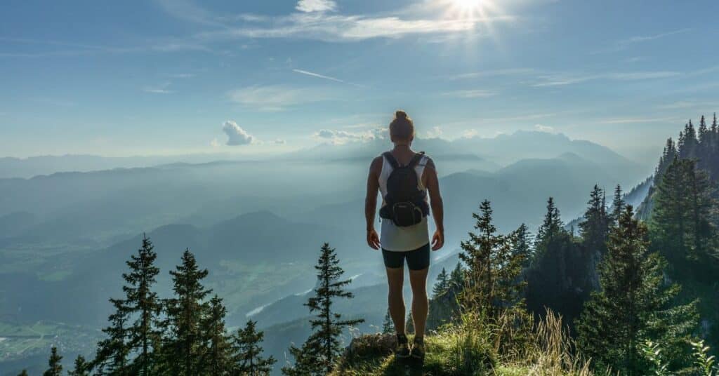 Woman stands on mountain top overlooking epic viewpoint, Setting Health Goals