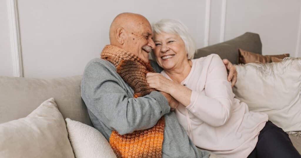 Older couple embraces happily on their couch, confused about nutrition