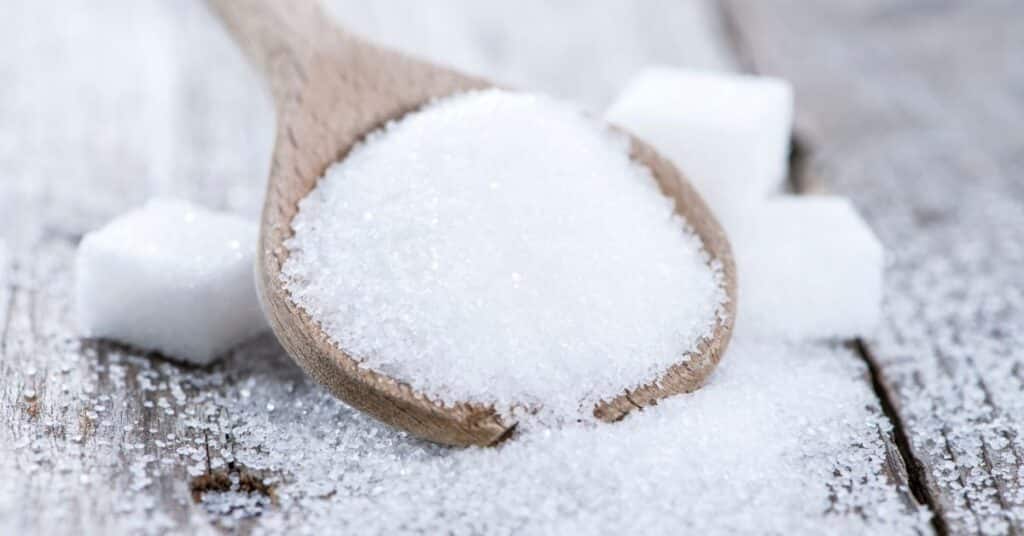 A large scoop of sugar in a wooden spoon, is sucralose bad for your gut