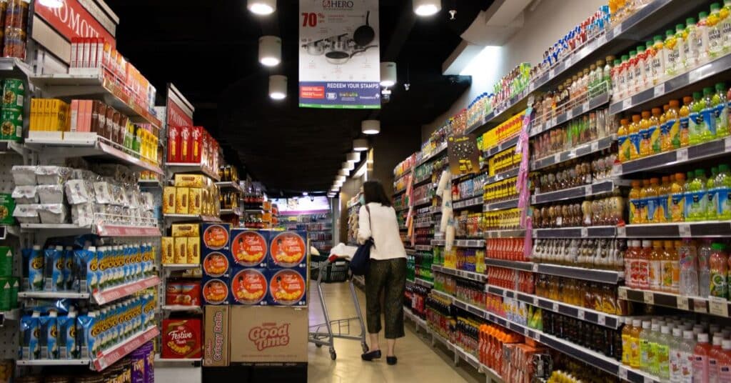 A woman walks through a super market aisle filled with all kinds of processed foods and products, is sucralose bad for your gut