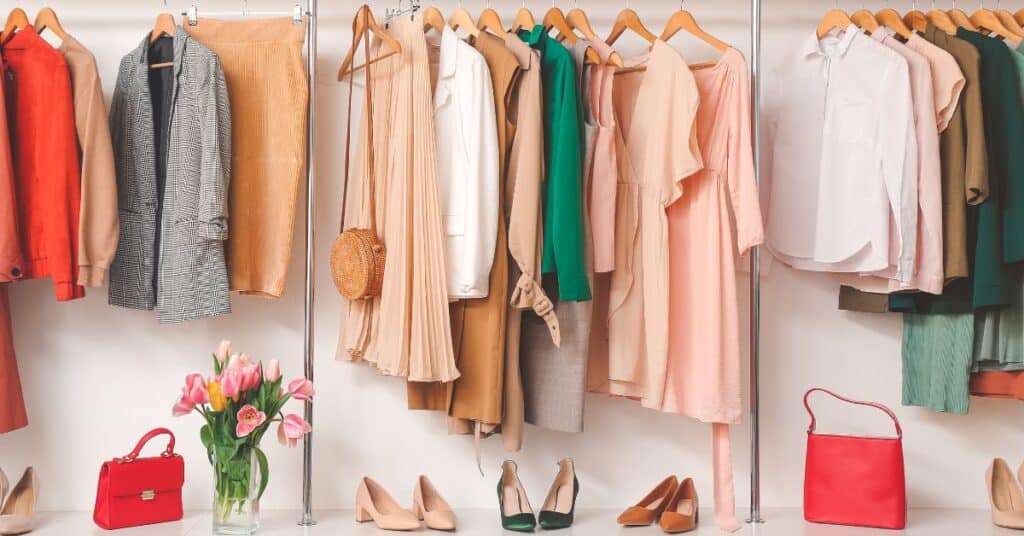 A colorful wardrobe on a clothing rack with various purses and heels on the shelf below them