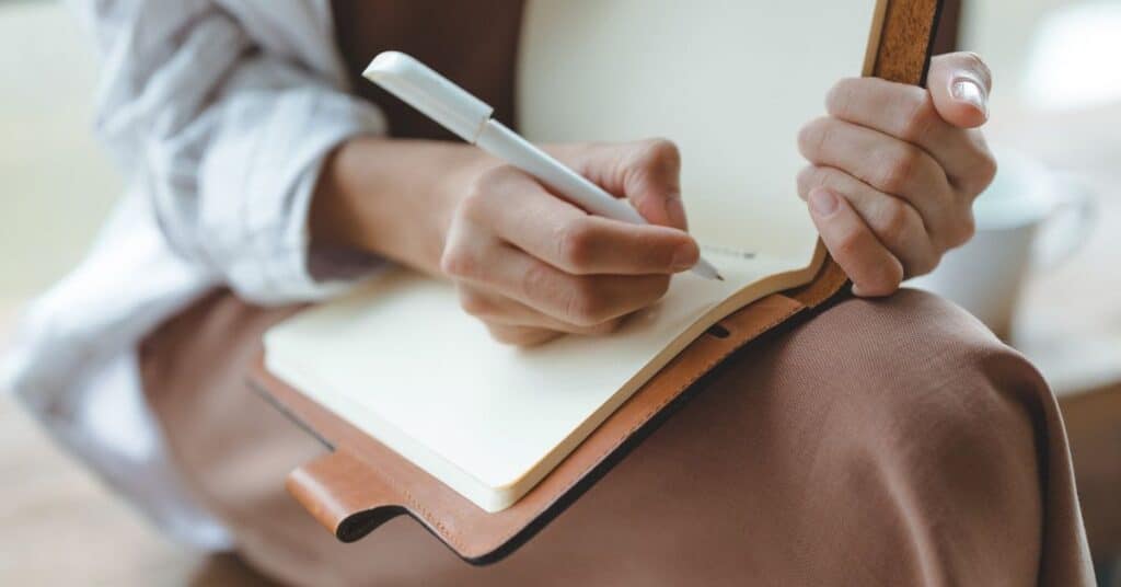 A woman journals in a leather bounder notebook, ways to boost mood instantly