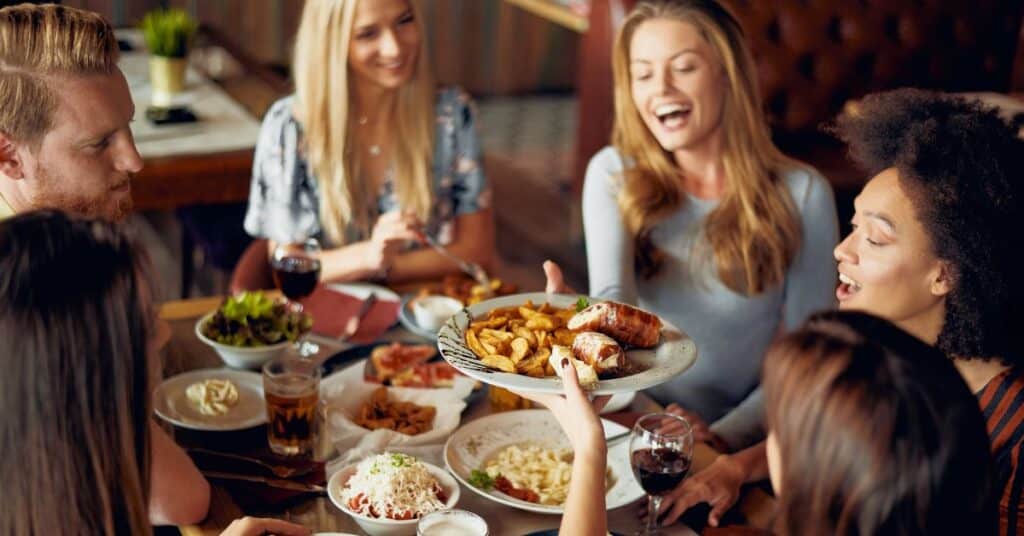 Lots of smiles around a table of friends sharing food, ways to boost mood instantly