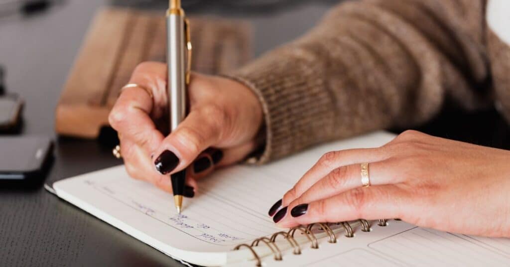 A woman's hands writing in a journal