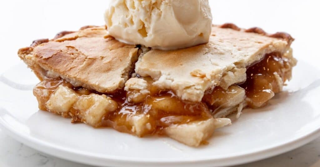 A slice of apple pie with a dollop of vanilla ice cream on top, holiday IBS flare up