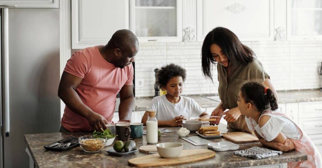 A mom and dad show their kids how to make breakfast in their kitchen, prioritizing health