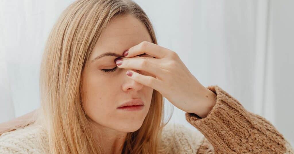 A woman holds her hand up to her brow as if she is stressed and overwhelmed, digestive symptoms