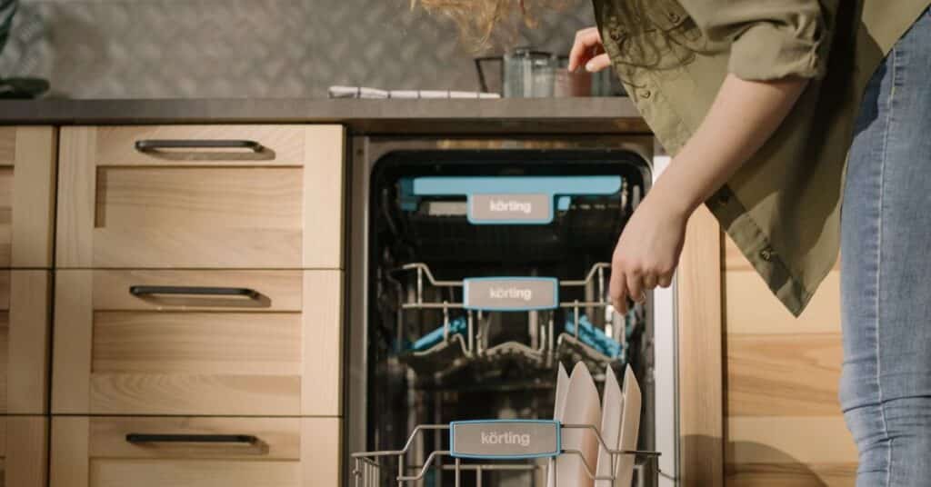 A woman unloads a clean dishwasher, hot mess mom culture